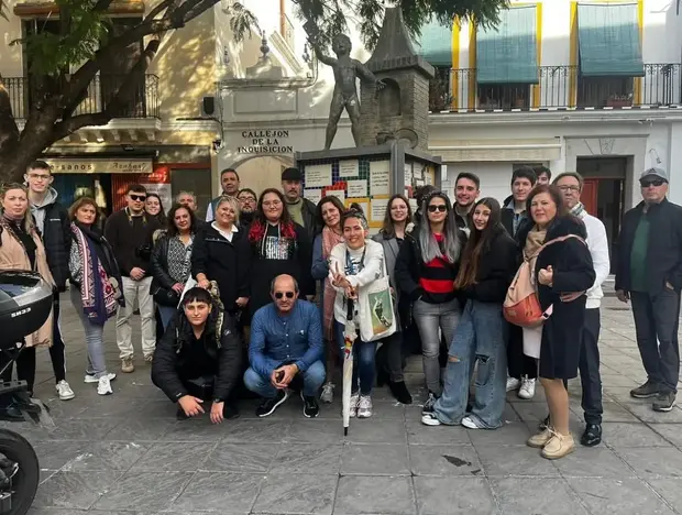 Grupo de personas posando frente a la Casa de la Moneda en Sevilla.