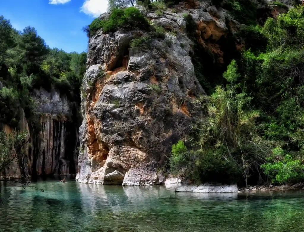 Paisaje natural con agua cristalina y roca escarpada bajo cielo azul, Chulilla.