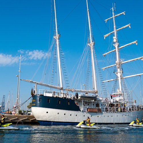 Barco anclado en puerto con personas en motos acuáticas, texto: 'Seguridad y normas de navegación'.