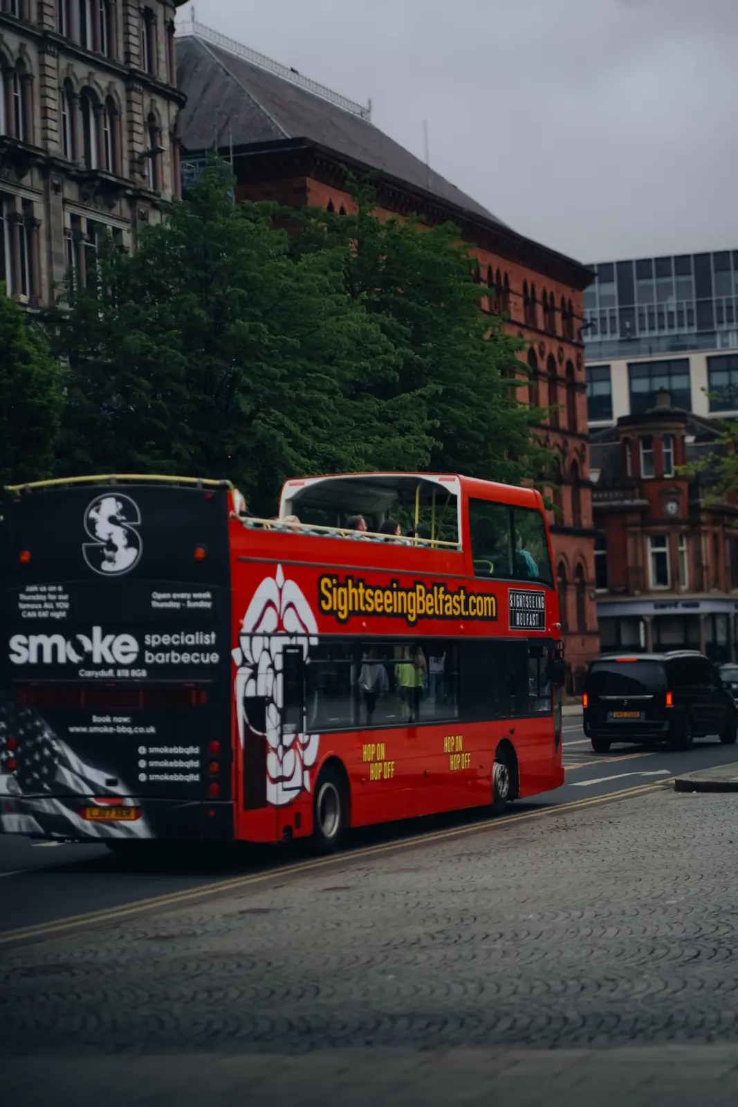 Red sightseeing bus travelling through central Belfast