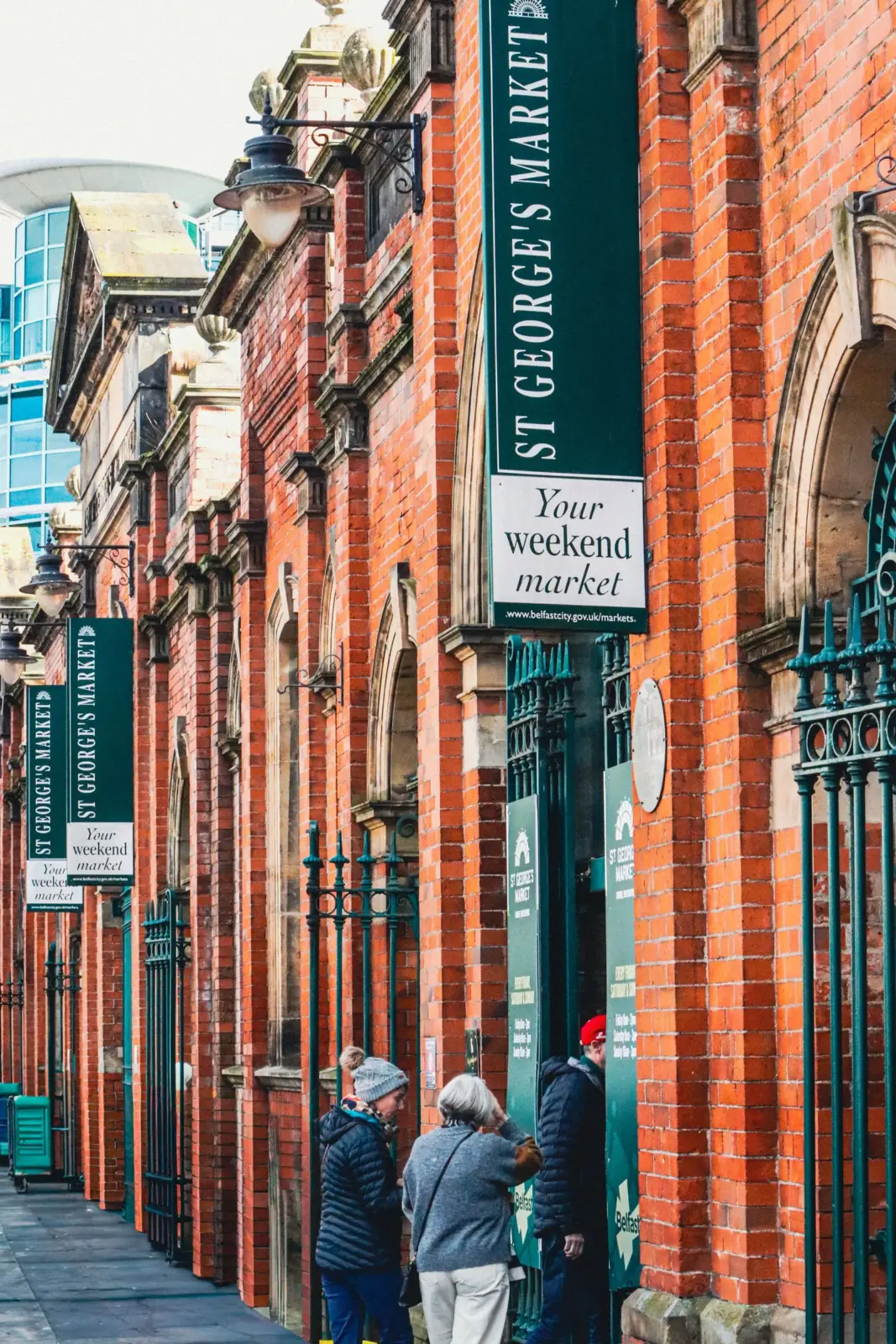 Visitors entering St George's Market beside its red-brick facade in Belfast