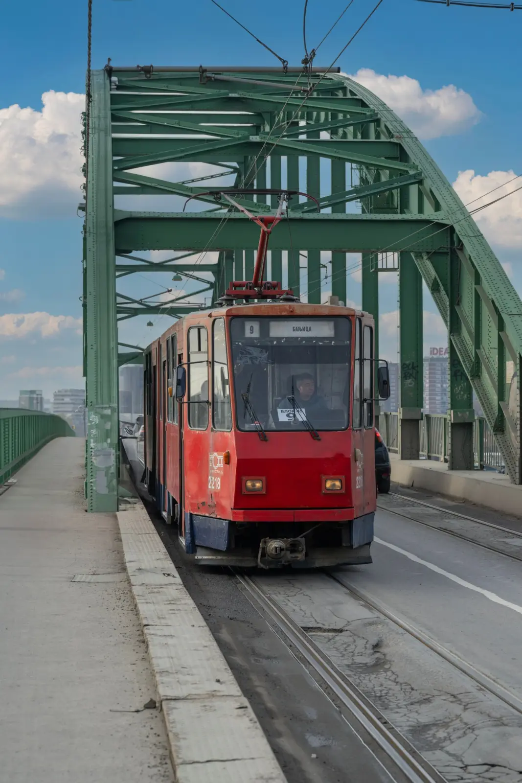 Tranvía rojo de la línea 9 hacia Banjica sobre un puente metálico de Belgrado
