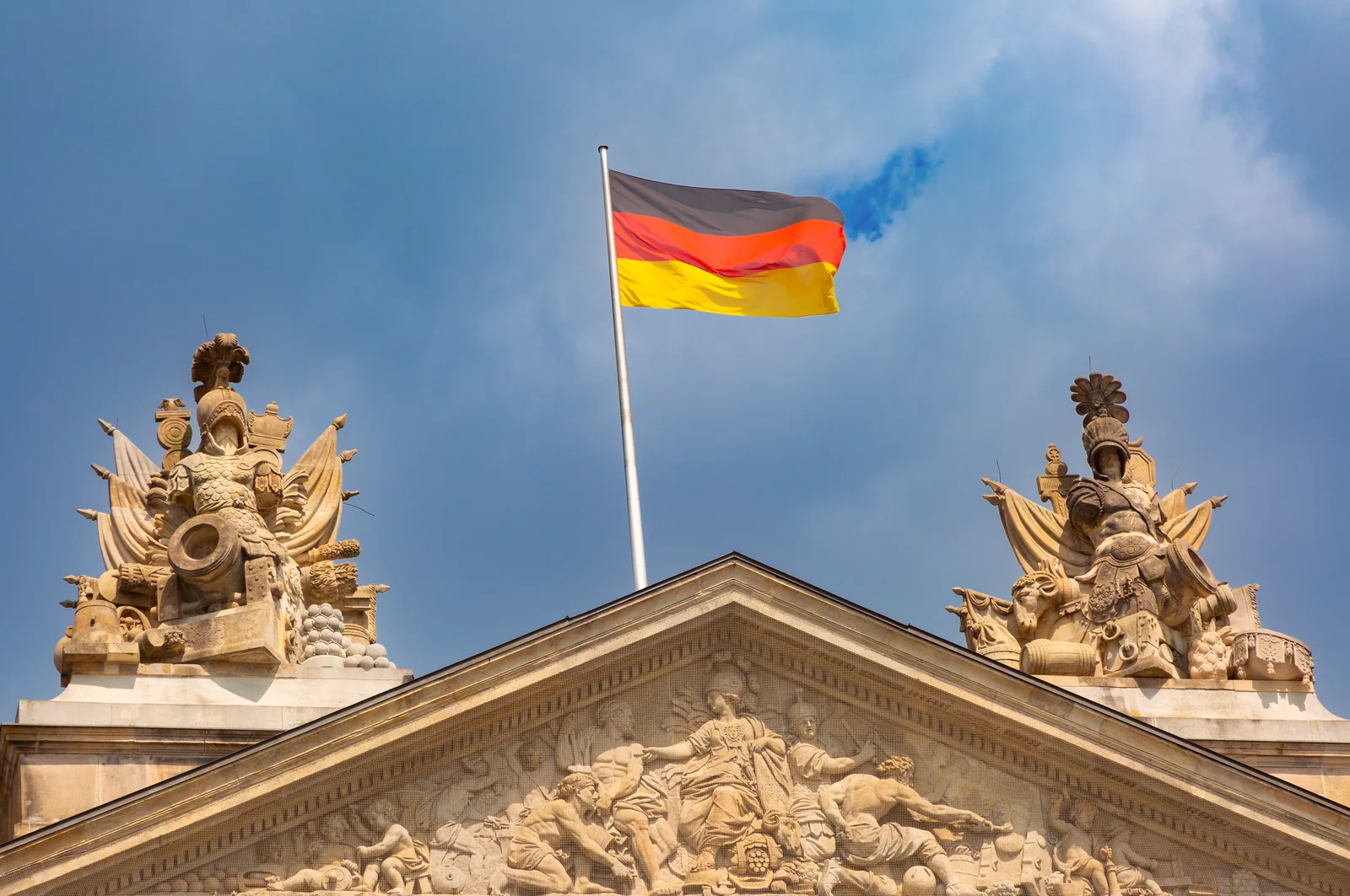 German flag flying on a historic building under cloudy Berlin skies