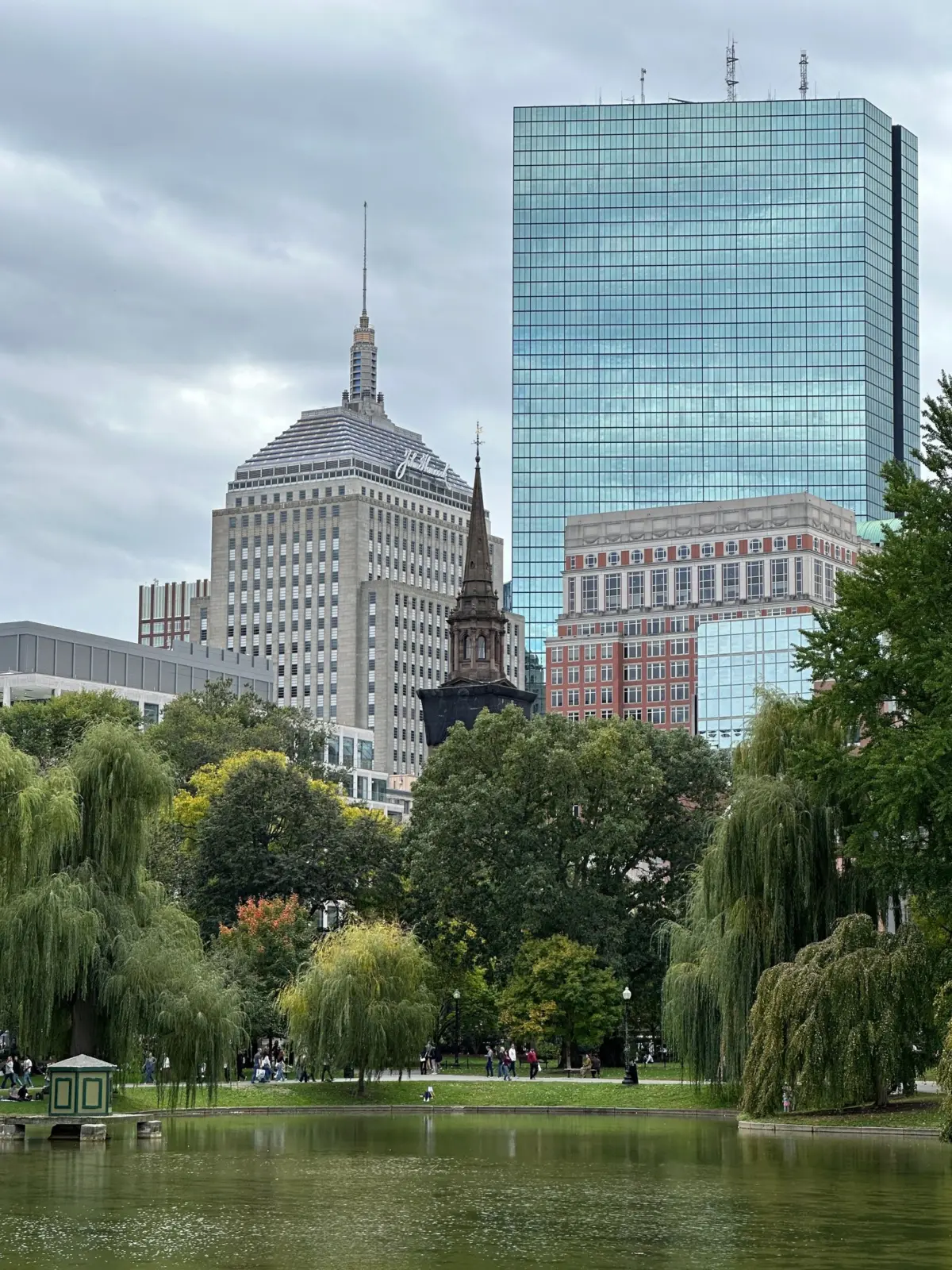 Boston Public Garden lagoon, willow trees and paths beneath the city skyline