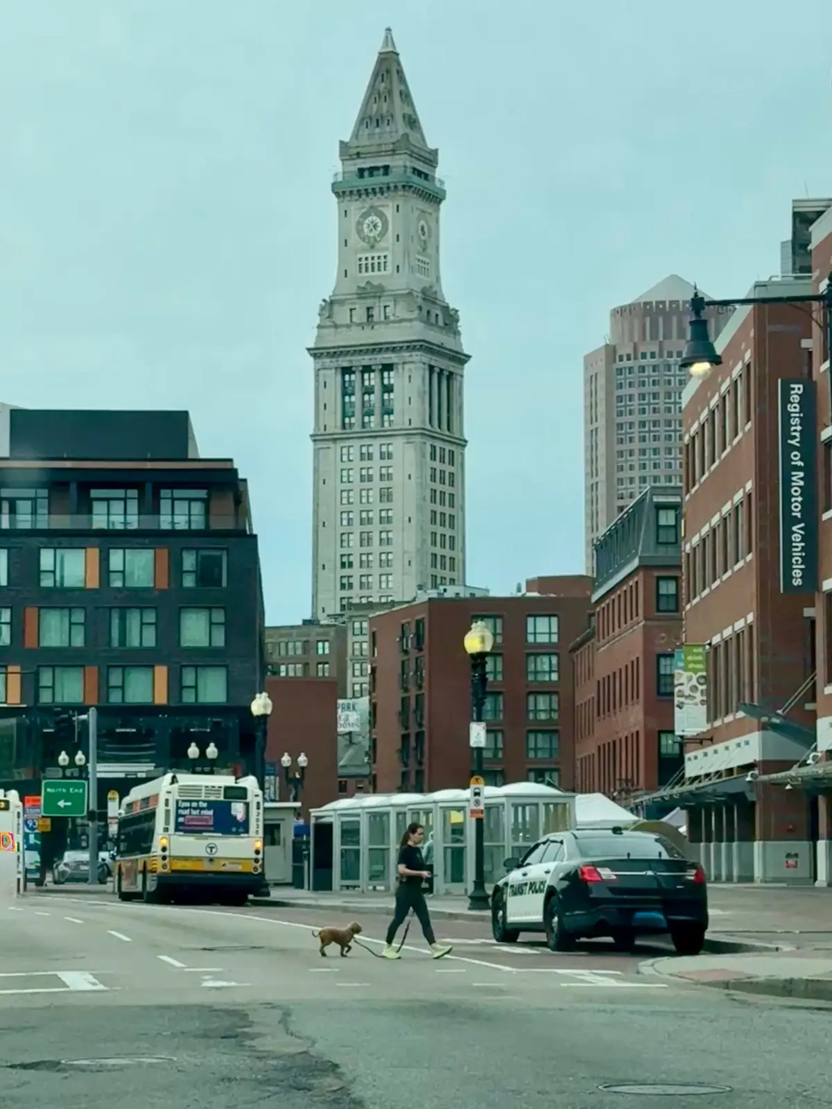 MBTA buses and a pedestrian beneath the Custom House Tower in downtown Boston