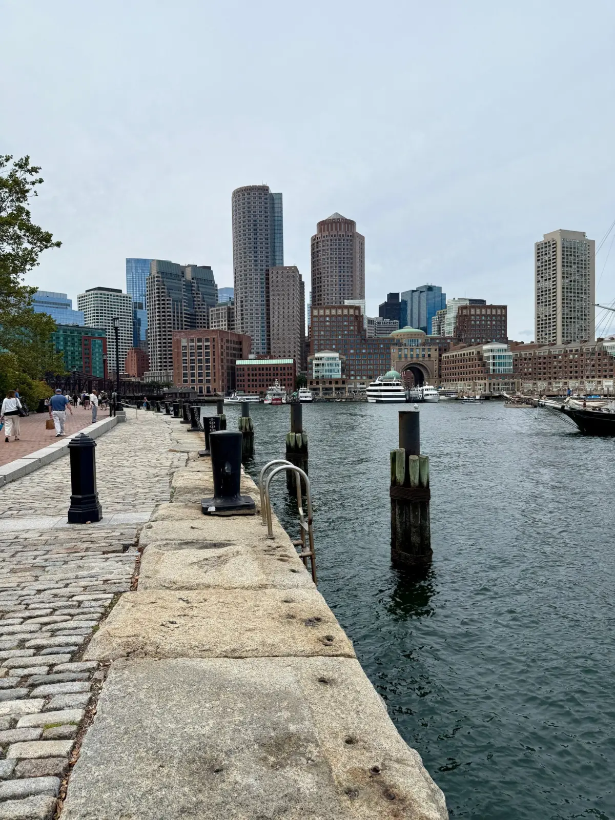 Boston Harborwalk beside the harbor, with Rowes Wharf and the downtown skyline across the water