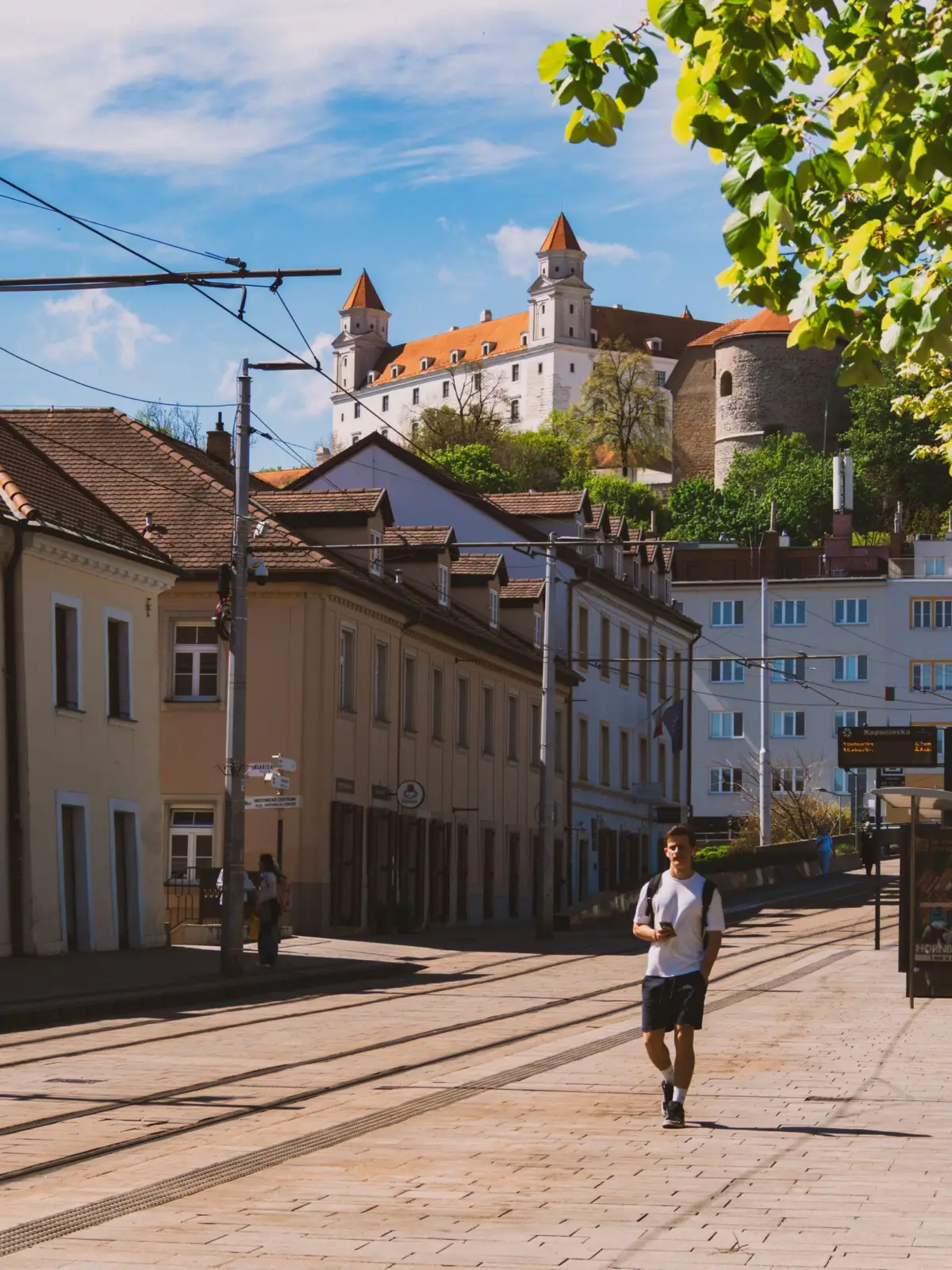 Peatón caminando por una calle de Bratislava con el castillo al fondo