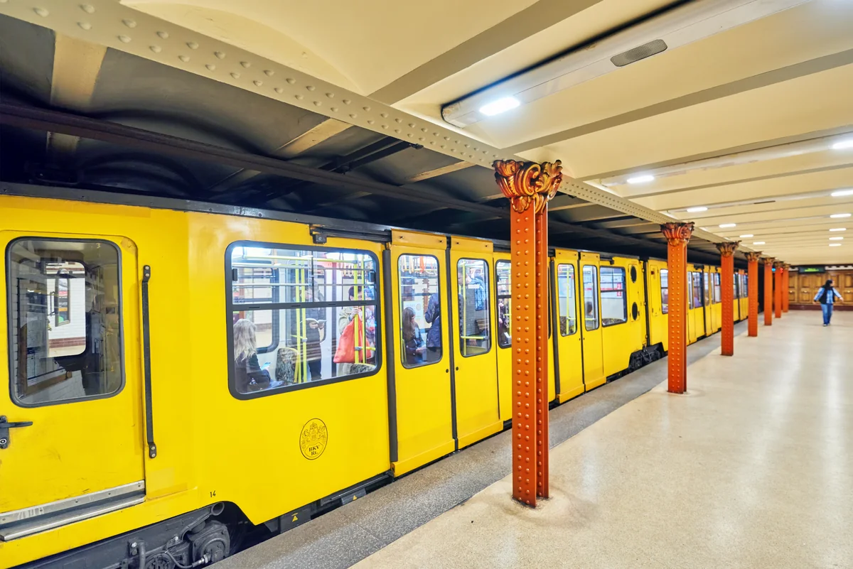 Tren amarillo de la línea 1 del metro de Budapest en una estación histórica de columnas rojas