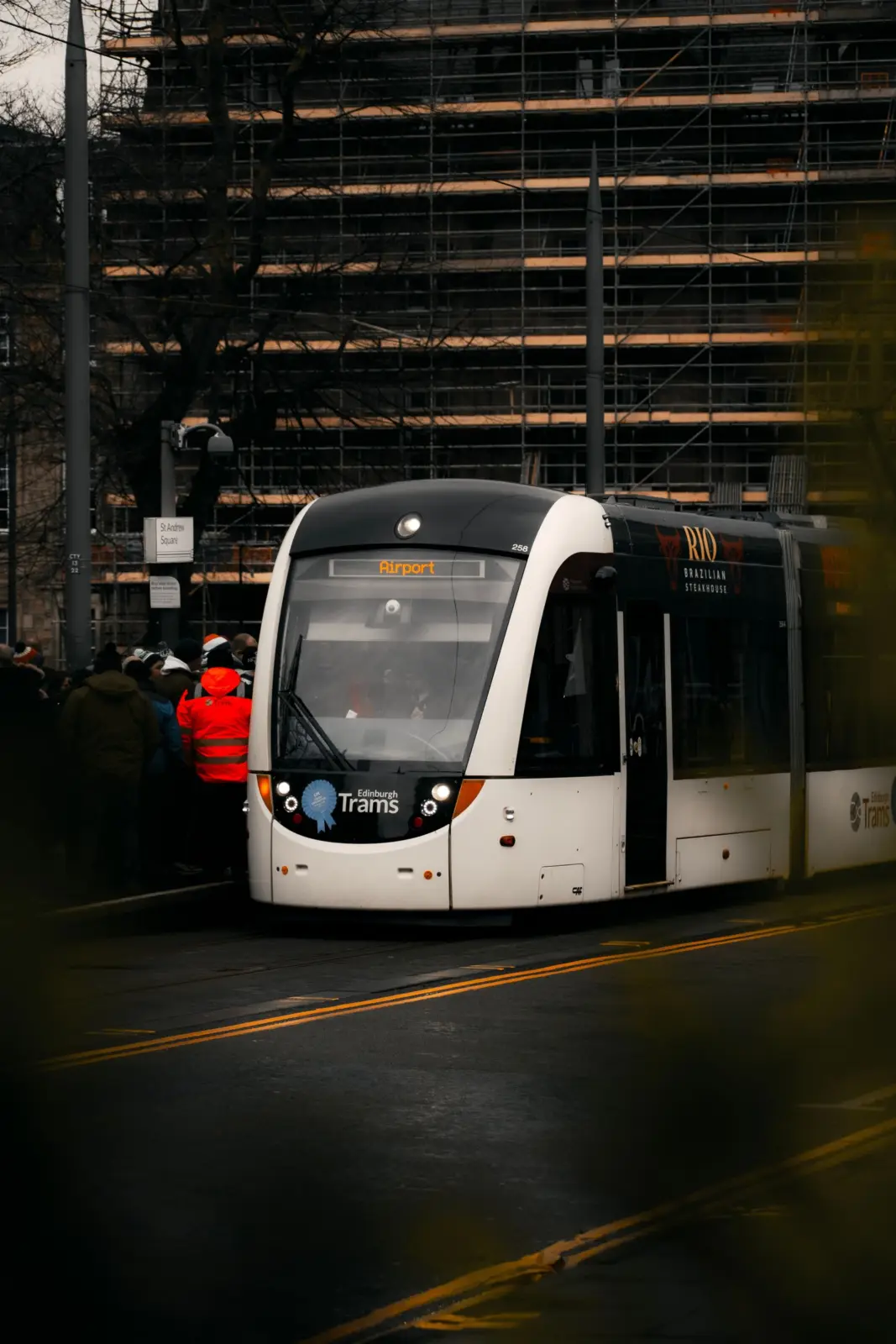 Edinburgh Airport tram beside waiting passengers on a city street