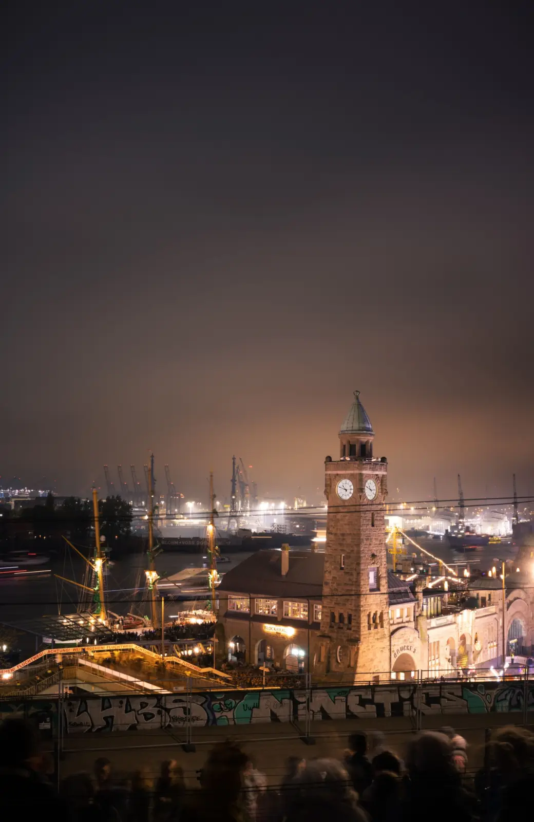 Torre del reloj de Landungsbrücken iluminada junto al puerto de Hamburgo de noche