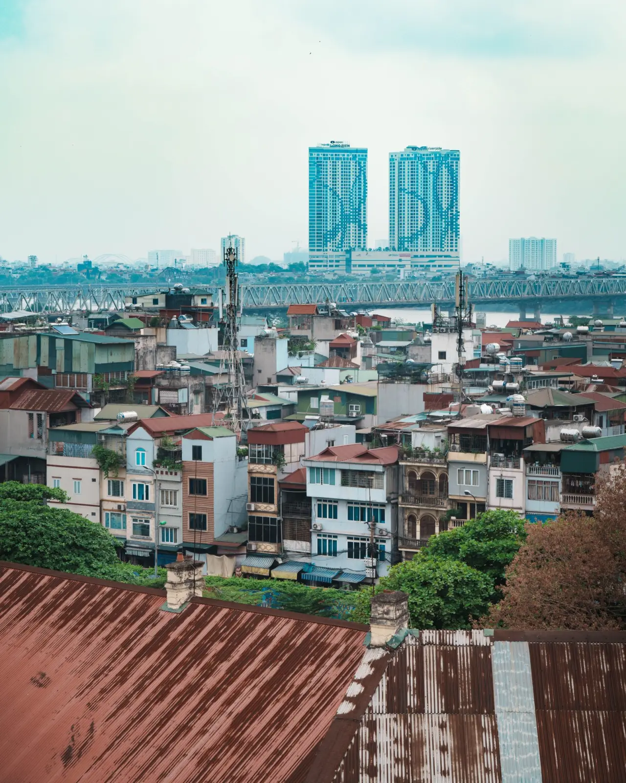 Panorama urbano de Hanói con tejados, un puente metálico y dos torres modernas