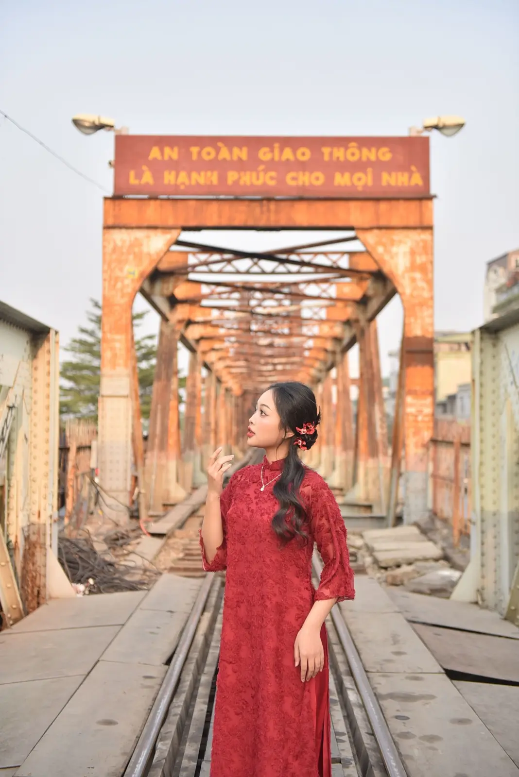 Mujer con vestido rojo sobre las vías del puente Long Biên en Hanói