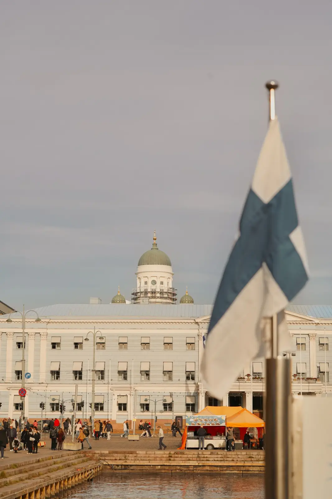 Bandera finlandesa, mercado junto al puerto y cúpula de la catedral de Helsinki