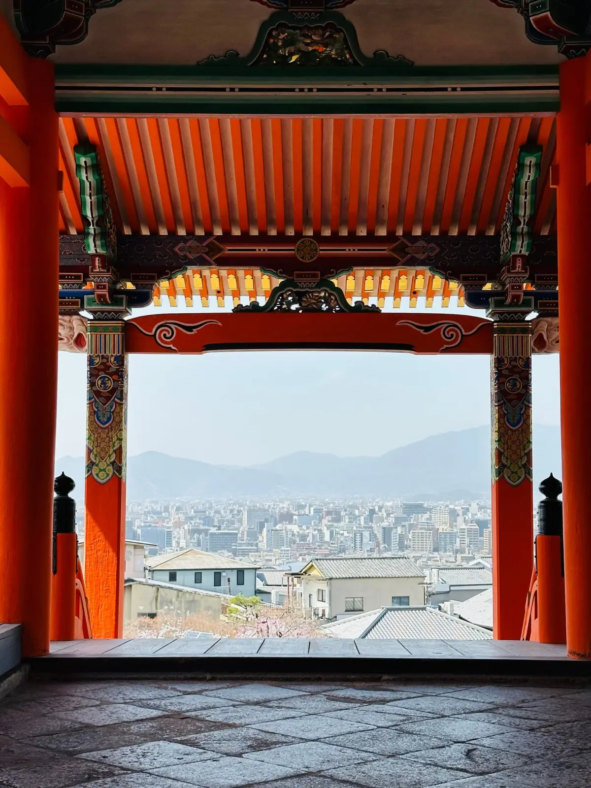 Vista panorámica de Kioto enmarcada por la estructura roja de un templo