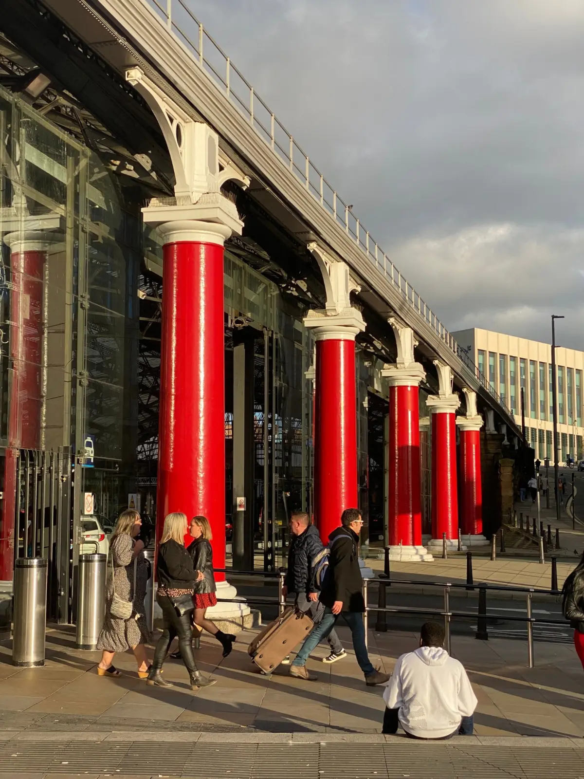Viajeros con equipaje ante las columnas rojas de la estación Liverpool Lime Street