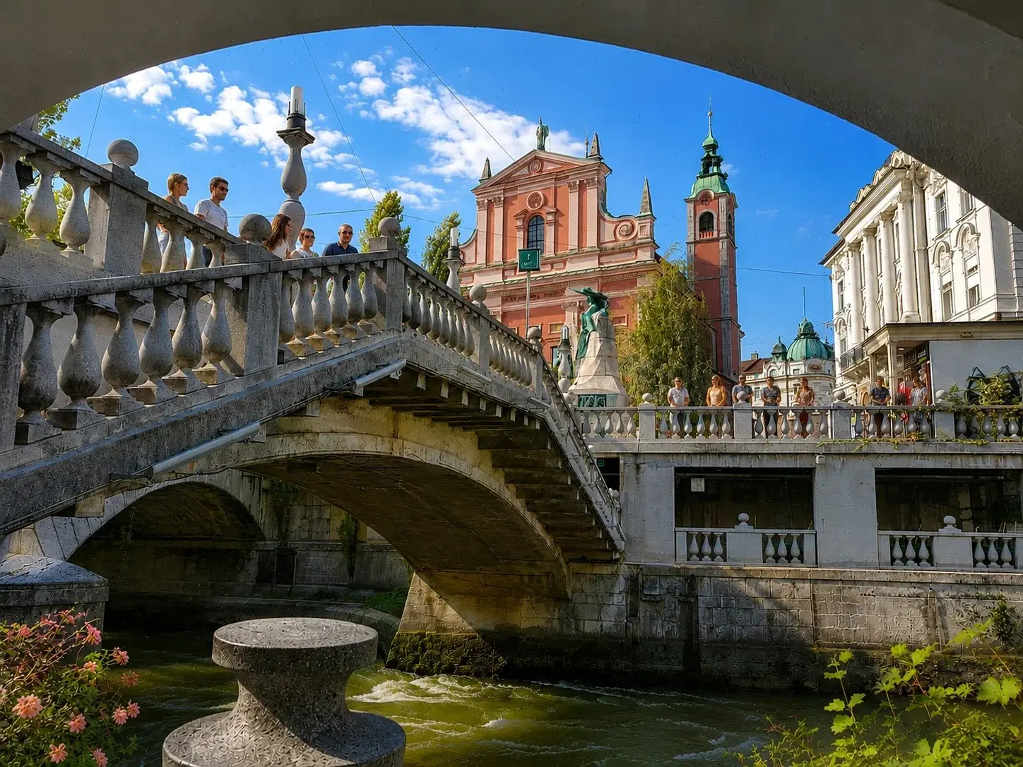 Visitantes recorren el Puente Triple sobre el río Ljubljanica, frente a la iglesia franciscana de Liubliana