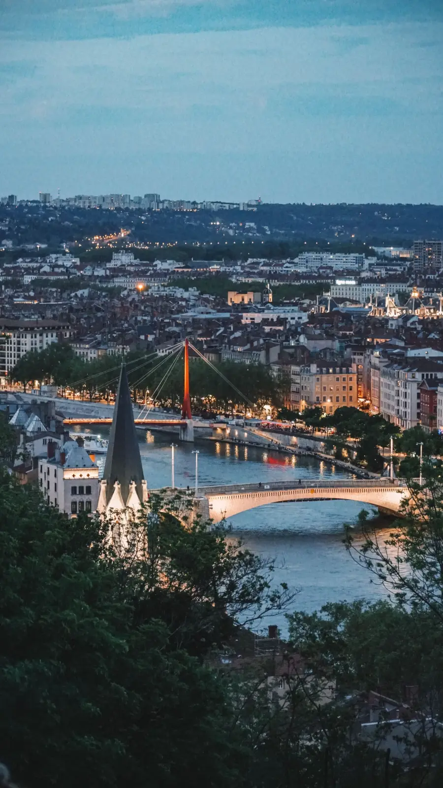 Vista panorámica de Lyon al atardecer, con el río, varios puentes y el perfil urbano