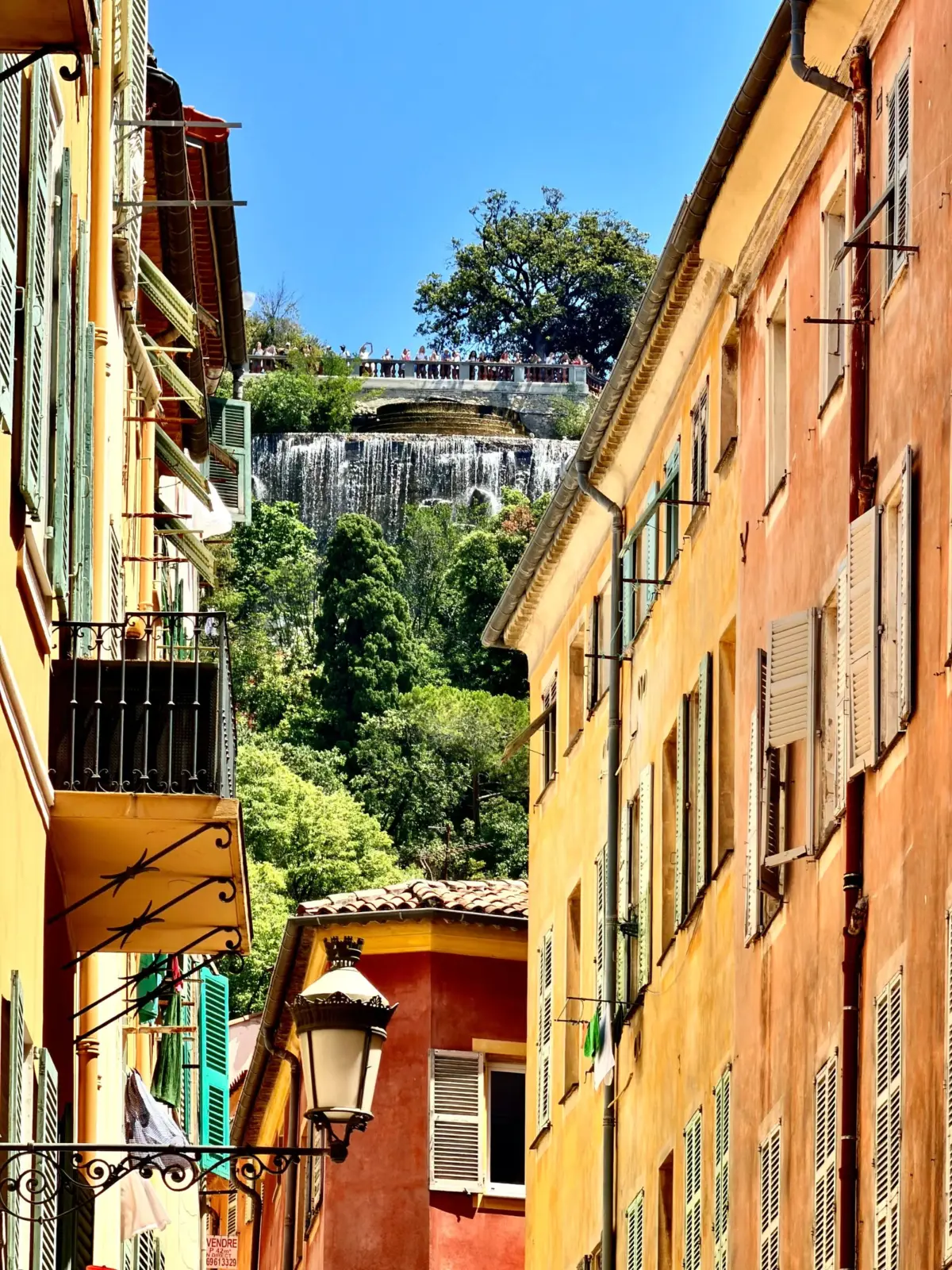 Fachadas de Vieux-Nice con la cascada de la Colina del Castillo al fondo, Niza