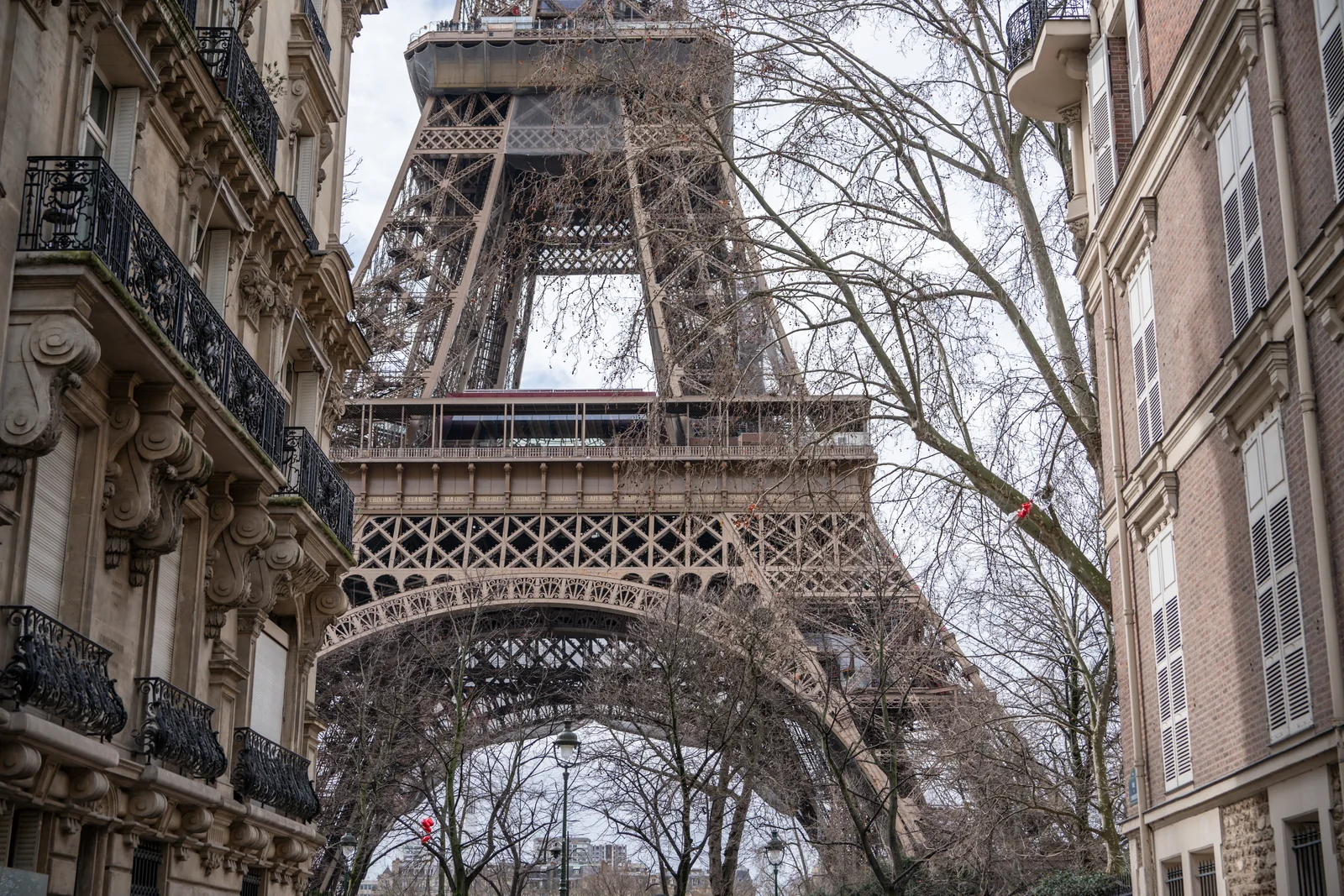 Hombre caminando por una calle de París con la Torre Eiffel entre edificios
