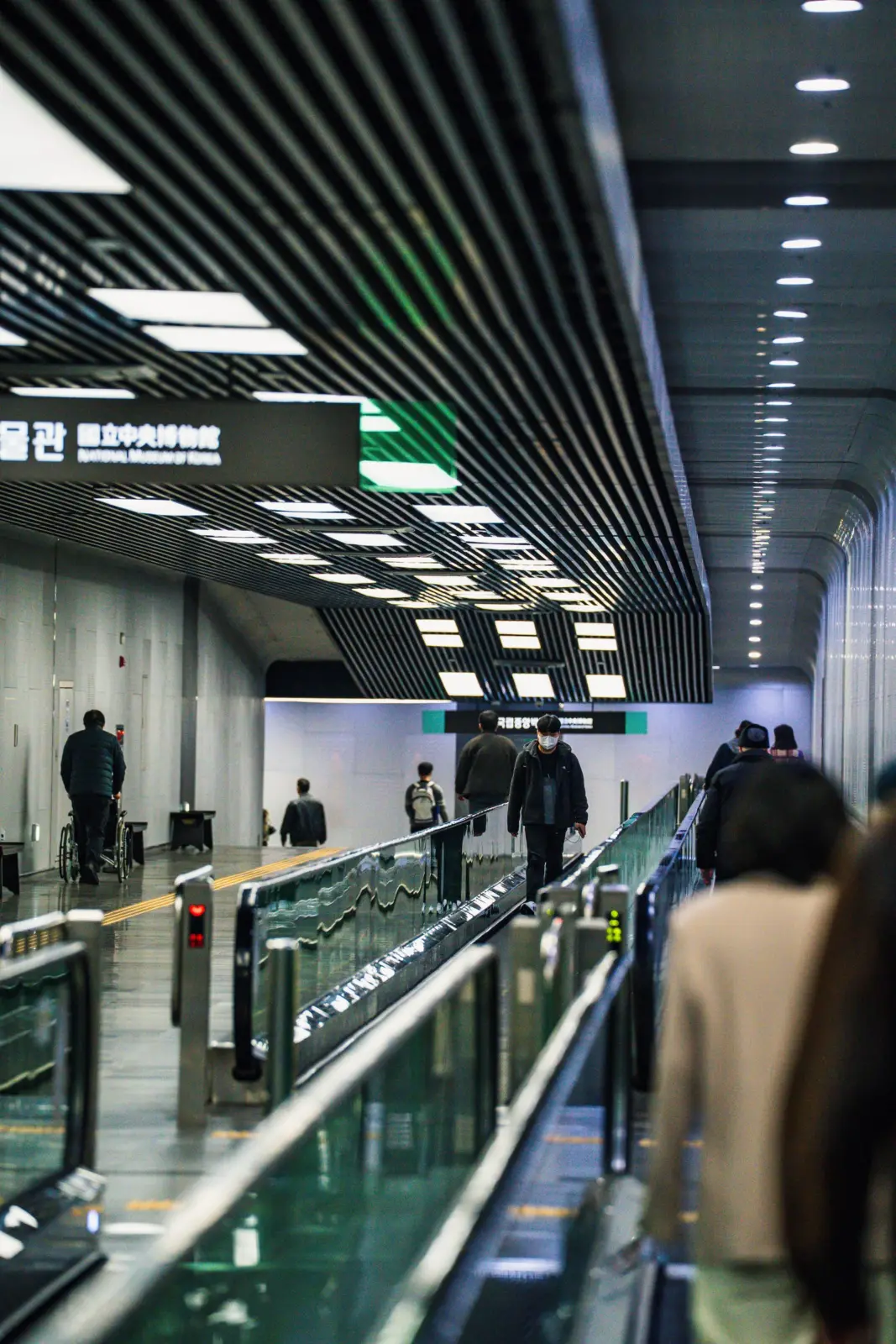 Pasillo del metro de Seúl con pasarelas móviles y viajeros