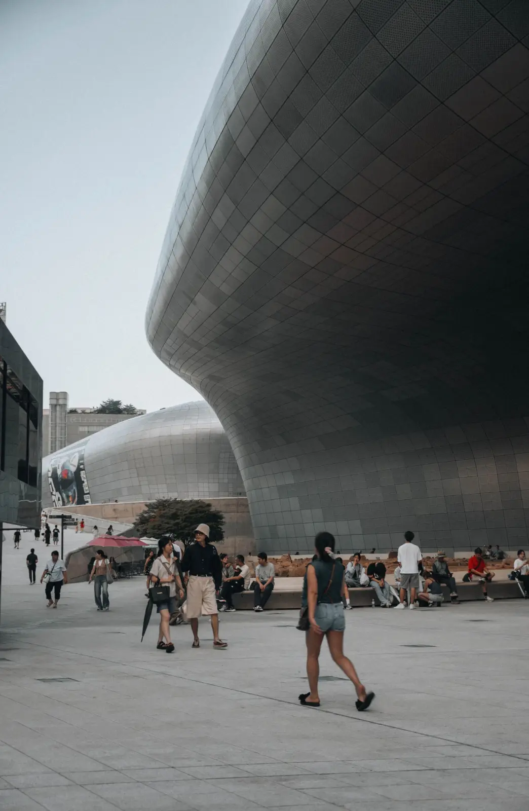 Fachadas curvas del Dongdaemun Design Plaza en Seúl con visitantes en la plaza