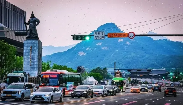 Tráfico en Sejong-daero ante la puerta Gwanghwamun y las montañas de Seúl