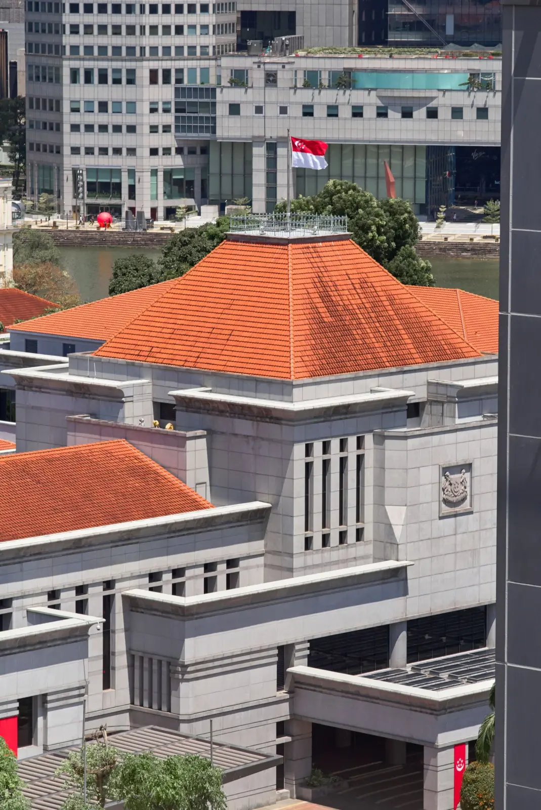 Parlamento de Singapur con tejados rojos y la bandera nacional entre edificios del centro