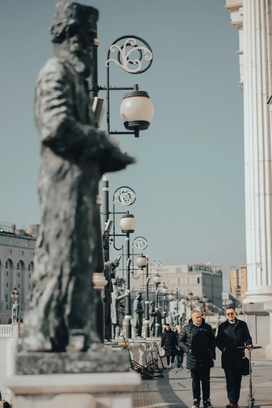Paseantes entre estatuas y farolas ornamentales en el centro de Skopje