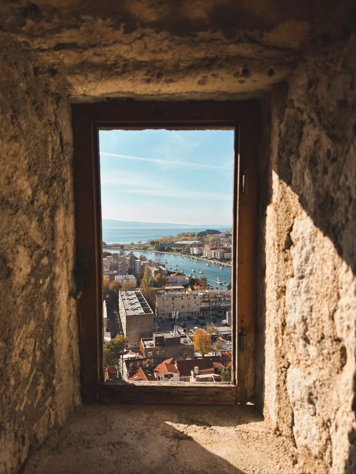 Puerto y tejados de Split vistos a través de una ventana de piedra