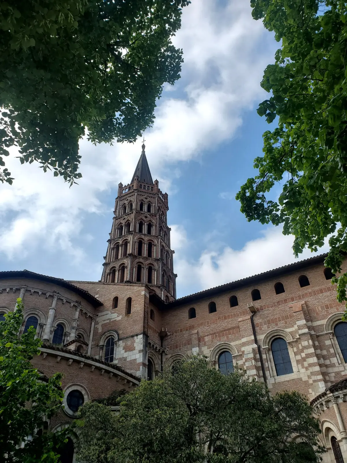 Torre y exterior de la basílica de Saint-Sernin en Toulouse entre árboles