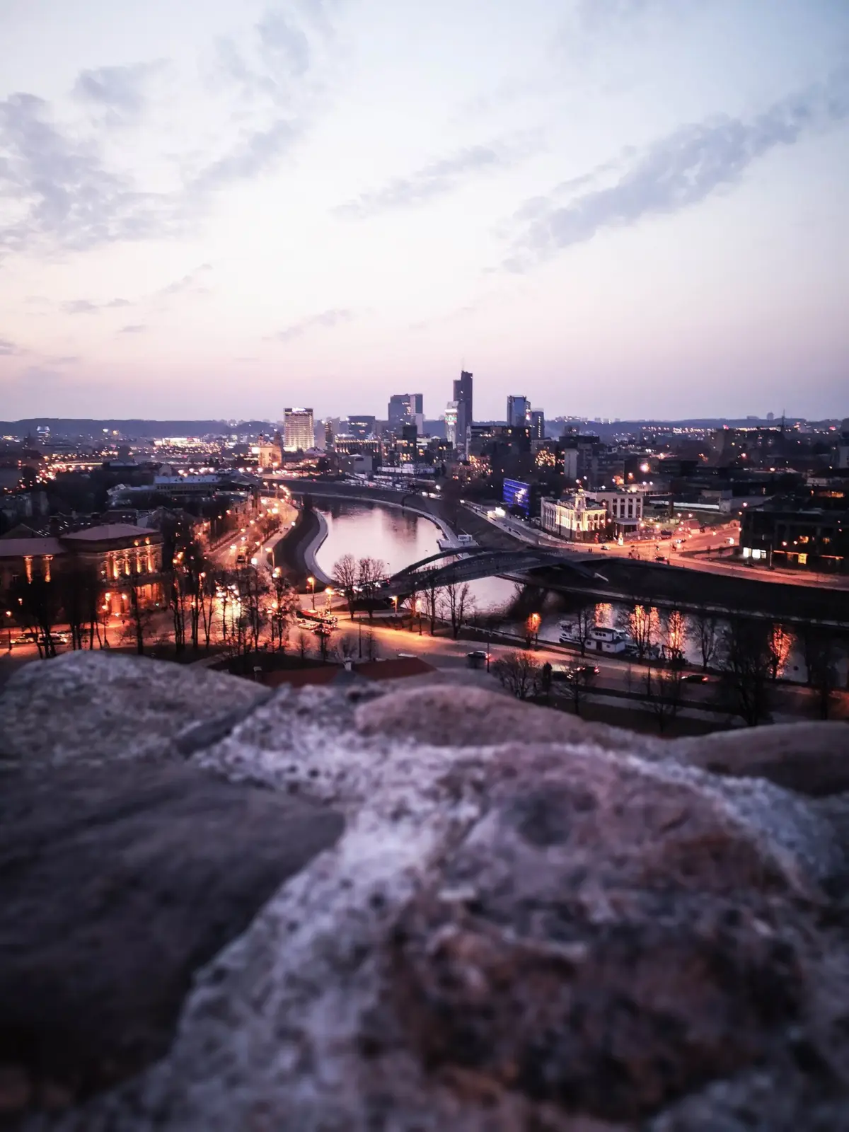 Vista panorámica de Vilnius al anochecer, con el río Neris, puentes y edificios iluminados